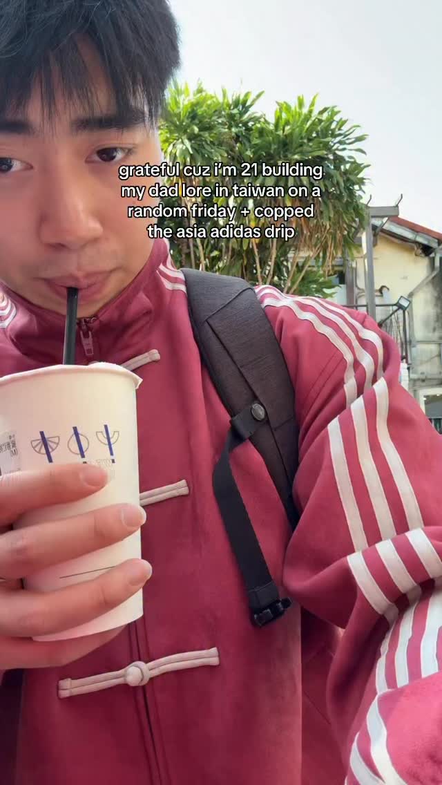 Anderson in a red Adidas jacket with a drink outdoors in Taiwan